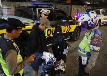 PERIKSA : Personel gabungan memeriksa surat-surat dan barang bawaan pengendara sepeda motor saat menggelar razia KRYD, Sabtu (13/7/2024) malam. (Foto Dok/Humas Polres)