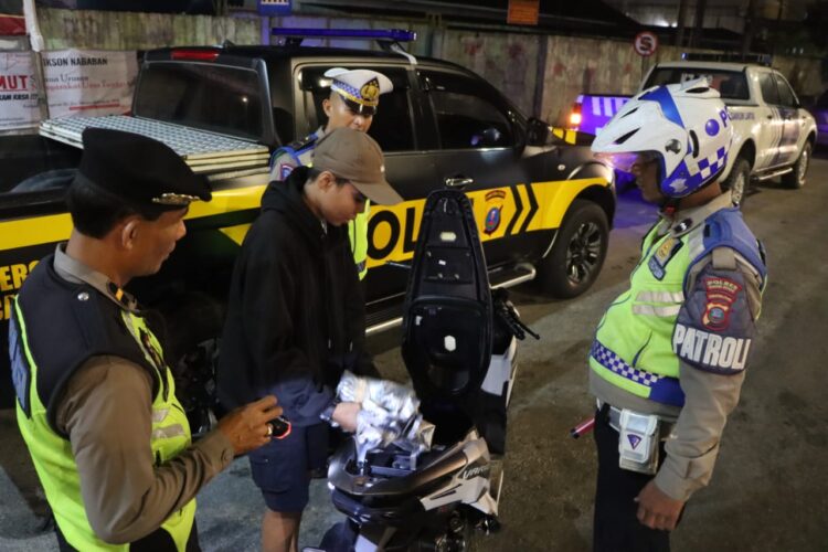 PERIKSA : Personel gabungan memeriksa surat-surat dan barang bawaan pengendara sepeda motor saat menggelar razia KRYD, Sabtu (13/7/2024) malam. (Foto Dok/Humas Polres)