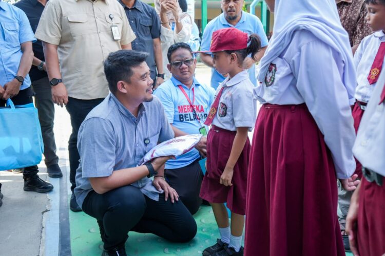 SERAHKAN BANTUAN: Wali Kota Bobby Nasution didampingi Wakilnya H Aulia Rachman secara simbolis menyerahkan bantuan seragam dan peralatan sekolah kepada siswa kurang mampu di UPT SMPN 1 Medan, Selasa (16/7/2024). (Foto Ist)