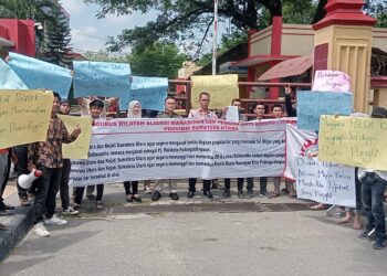BENTANGKAN BALIHO: Peserta aksi ALAMP AKSI membentangkan baliho saat demo di depan Mapolda Sumut, Jumat (16/8/2024). (Foto: Dok/T77)