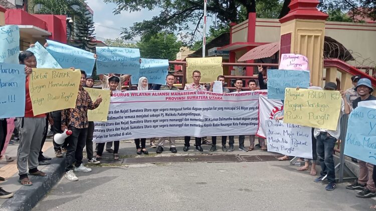BENTANGKAN BALIHO: Peserta aksi ALAMP AKSI membentangkan baliho saat demo di depan Mapolda Sumut, Jumat (16/8/2024). (Foto: Dok/T77)