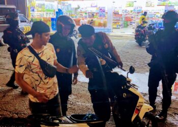 PERIKSA: Petugas Polres Pelabuhan Belawan melakukan pemeriksaan terhadap salah seorang pengendara sepeda motor, dalam kegiatan Patroli Gabungan cegah tindak kejahatan jalanan, Kamis dini hari (12/9/2024).(Foto Dok/Polres Belawan)