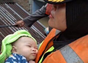 EVAKUASI BAYI : Kapolsek Medan Kota, Kompol Selvintriansih mengevakuasi bayi dan ibunya yang terjebak banjir, Rabu (27/11/2024). (Foto Screenshoot)