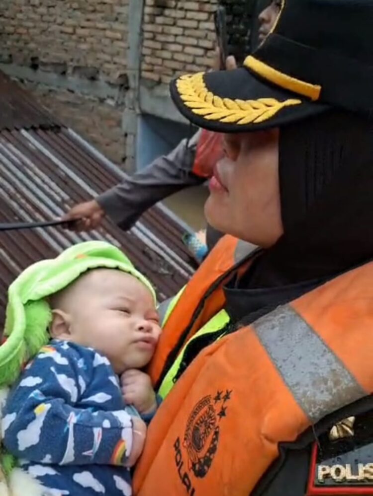 EVAKUASI BAYI : Kapolsek Medan Kota, Kompol Selvintriansih mengevakuasi bayi dan ibunya yang terjebak banjir, Rabu (27/11/2024). (Foto Screenshoot)