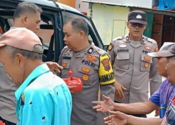 BAGI NASI BUNGKUS: Personel Polsek Belawan membagikan nasi bungkus kepada warga kurang mampu di kawasan Kota Pelabuhan Belawan, Jumat (13/12/2024).(Foto dok/Polres Belawan)