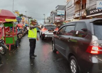 Kapos Pam TKB Ops Lilin Samrat 2024 bersama anggota dari kepolisian setempat melaksanakan kegiatan pengaturan arus lalu lintas di Jalan Walanda Maramis, tepatnya di depan New Bendar, Minggu (22/12/2024).