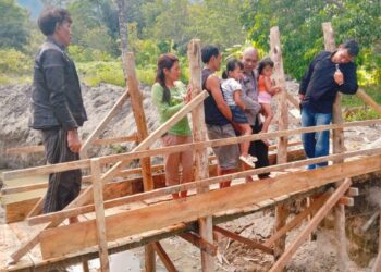 AIPDA Tumbur B. Sitohang, personel Bhabinkamtibmas Desa Unjur Kecamatan Simanindo Kabupaten Samosir, berinisiatif membangun jembatan kayu di lokasi yang sempat viral di media sosial rumah dikelilingi parit.