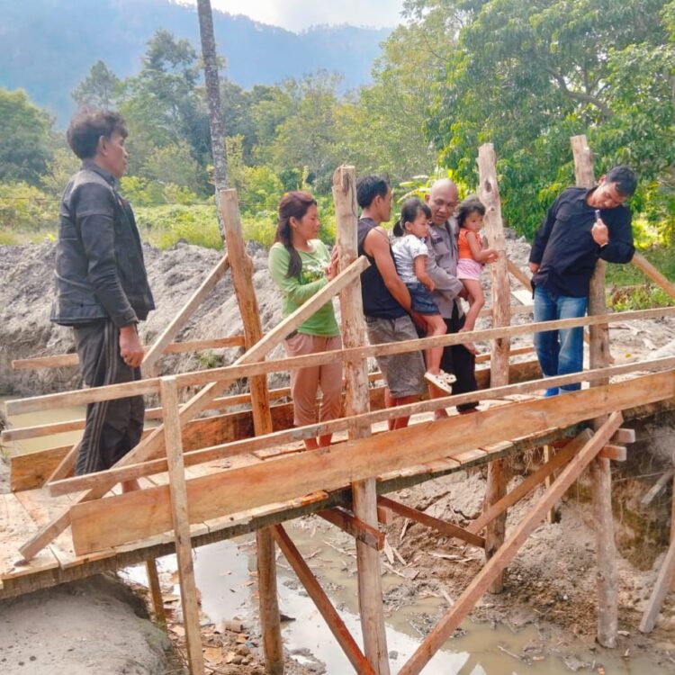 AIPDA Tumbur B. Sitohang, personel Bhabinkamtibmas Desa Unjur Kecamatan Simanindo Kabupaten Samosir, berinisiatif membangun jembatan kayu di lokasi yang sempat viral di media sosial rumah dikelilingi parit.