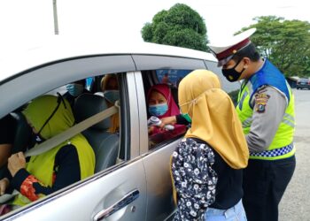 Petugas sedang mengecek suhu tubuh seorang penumpang mini bus (Hari Pramana/Nusantara Netizen)