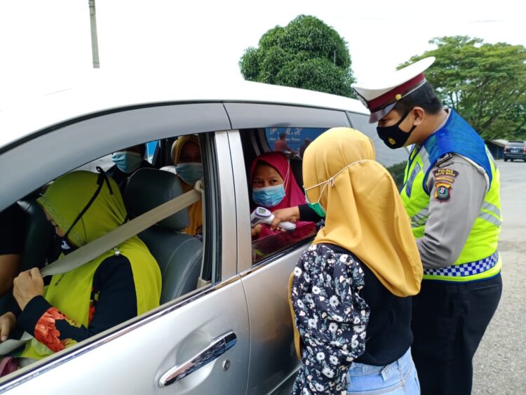 Petugas sedang mengecek suhu tubuh seorang penumpang mini bus (Hari Pramana/Nusantara Netizen)
