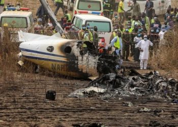 Para petugas berwenang berusaha menangani bangkai pesawat yang jatuh di dekat Bandara Abuja, Nigeria, Minggu (21/2/2021). (Foto: Reuters)