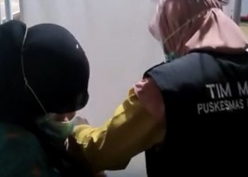 Petugas vaksin memegangi tenaga kesehatan yang takut disuntik. (Foto: iNews/Herman Amiruddin).