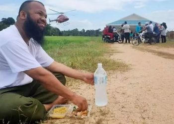 Muhammad Azlan Al Amin makan di pinggir jalan dengan latar belakang helikopter yang membawa warga (Foto: Dok Pribadi)