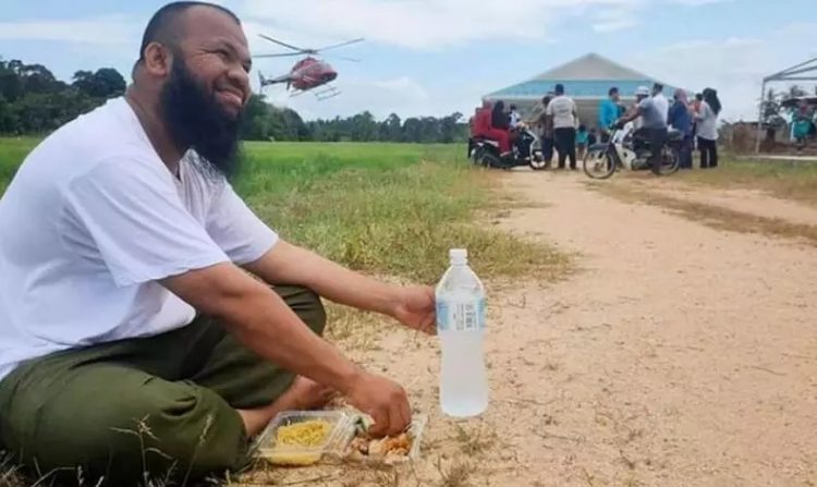 Muhammad Azlan Al Amin makan di pinggir jalan dengan latar belakang helikopter yang membawa warga (Foto: Dok Pribadi)