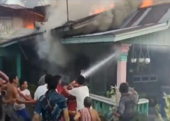 Petugas Damkar dibantu warga semprotkan air ke rumah terbakar di Kecamatan Tanjungbalai, Asahan, Senin (26/4/2021) sore. (Foto : iNews/Ulil Amri)