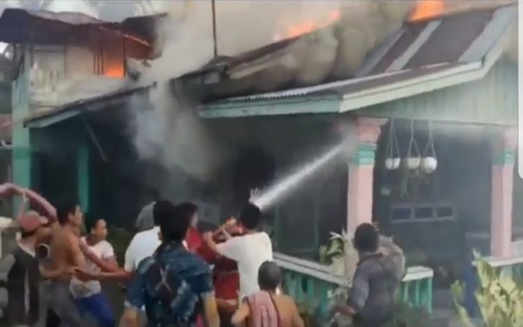 Petugas Damkar dibantu warga semprotkan air ke rumah terbakar di Kecamatan Tanjungbalai, Asahan, Senin (26/4/2021) sore. (Foto : iNews/Ulil Amri)
