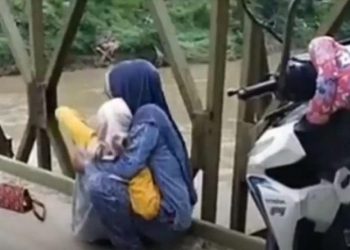 Tangkapan layar saat warga menolong perempuan yang coba bunuh diri meloncat dari atas jembatan di Asahan. (foto: iNews/Ulil Amri)