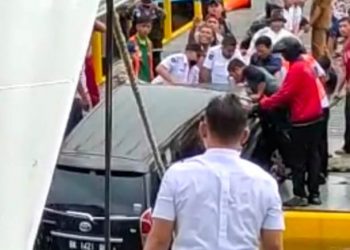 Petugas dibantu warga saat berusaha menarik mobil dari Danau Toba.