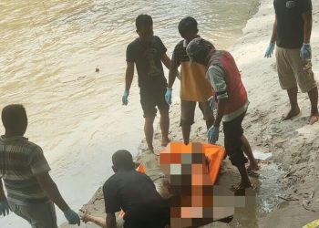 Petugas dibantu warga saat mengevakuasi mayat korban.