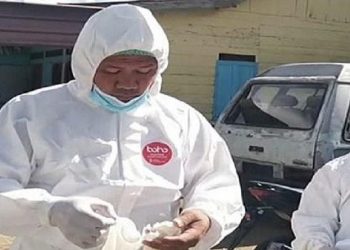 Kapolsek Dolok Sanggul Iptu Tukkar L Simamora mengenakan APD untuk memakamkan jenazah pasien Covid-19. (Foto: Ist)