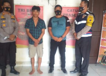 Pelaku penganiayaan (baju kotak - kotak) diapit petugas setelah diringkus dari Pasar Horas.