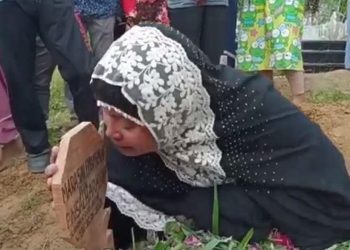 Bonia, istri wartawan korban penembakan OTK di Simalungun meratapi nisan suaminya. (Foto : iNews/Dharma Setiawan)