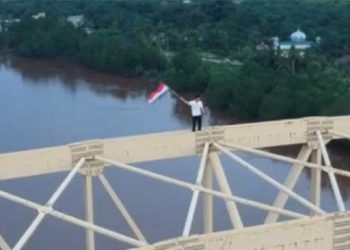 Aksi warga Siak mengibarkan bendera merah putih dari puncak jembatan. [Tangkapan layar]