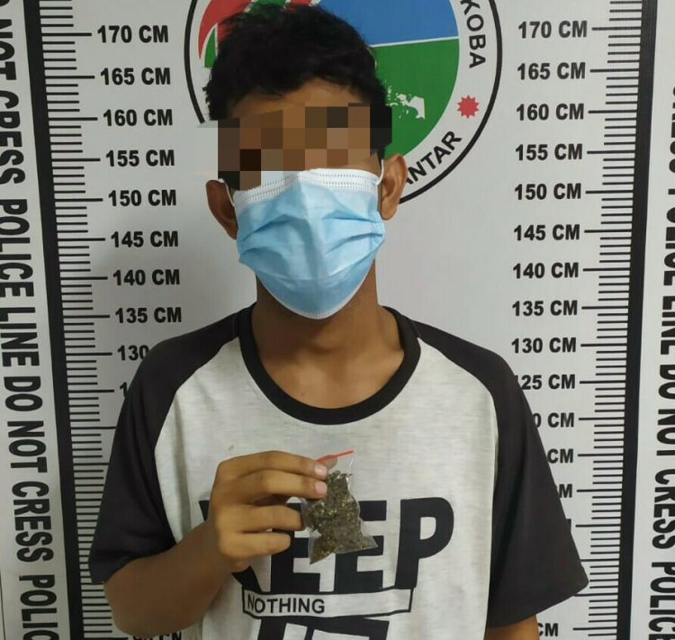 Foto pelaku Y memegang barang bukti ganja.