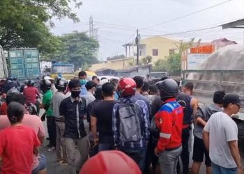 Warga berkerumun di lokasi kecelakaan mengerikan pengendara motor perempuan tewas terlindas truk kontainer di Belawan, Kota Medan. (foto: iNews/Yudha Bahar)