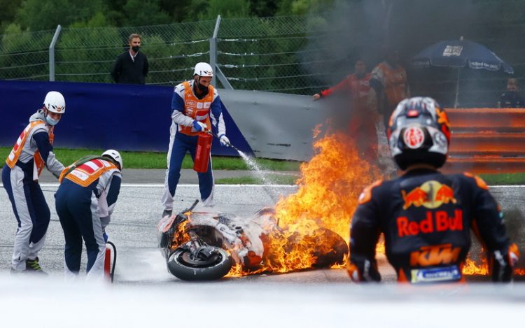 Pembalap Red Bull KTM Factory, Dani Pedrosa, menyaksikan motornya terbakar di Seri Styria, Spielber, Austria, pada Minggu (8/8/2021). (Foto: REUTERS/Borut Zivulovic)