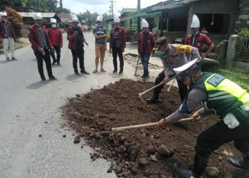 Kabag Ops Polres Simalungun, Kompol Suriyanto, tampak ikut timbun jalan rusak, di Sepanjang Jalan Siantar-Saribu Dolok.