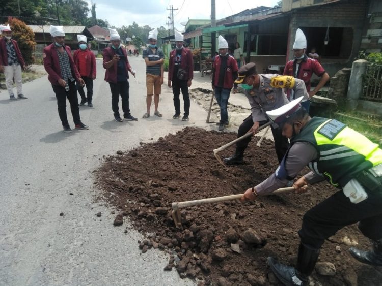 Kabag Ops Polres Simalungun, Kompol Suriyanto, tampak ikut timbun jalan rusak, di Sepanjang Jalan Siantar-Saribu Dolok.
