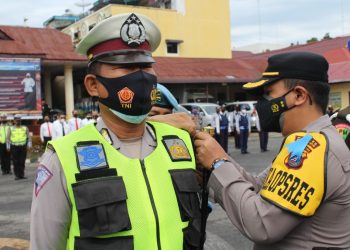 Kapolres Pematangsiantar, AKBP Boy Sutan Binaga Siregar S.I.K, menyematkan pita kepada salah seorang personel Sat Lantas Polres Pematangsiantar, tanda Operasi Patuh Toba 2021 resmi digelar.