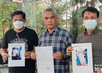 Pengacara PT Propernas Nusa Dua, Sastra (tengah), bersama keluarga korban menunjukkan foto kedua korban setelah ditusuk OTK. (Arfah/detikcom)