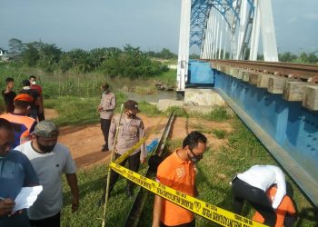 Petugas memasang garis polisi di lokasi penemuan mayat.