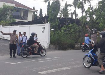 Petugas kepolisian tampak mengatur arus lalu lintas.