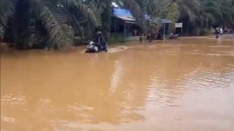 Seorang pengendara motor mendorong kendaraanya yang mogok akibat banjir di Madina. (Foto: iNews/Ahmad Husein Lubis).