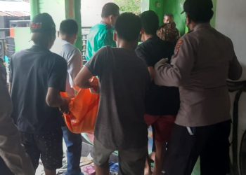 Petugas Kepolisian bersama warga saat mengevakuasi korban dari lokasi kejadian.