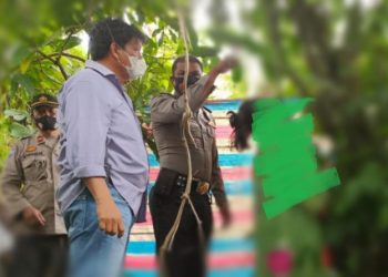 Petugas saat akan mengevakuasi jenazah korban yang masih tergantung di belakang rumahnya. Foto: Istimewa