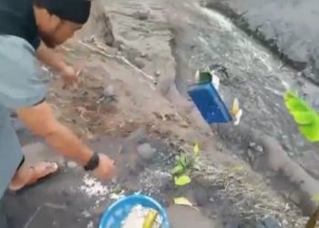 Aksi seorang pria mengenakan jubah warna abu-abu, dan rompi hitam dengan logo bendera merah putih menendang serta membuang sesajen di lokasi erupsi Gunung Semeru viral di media sosial. (Ist)