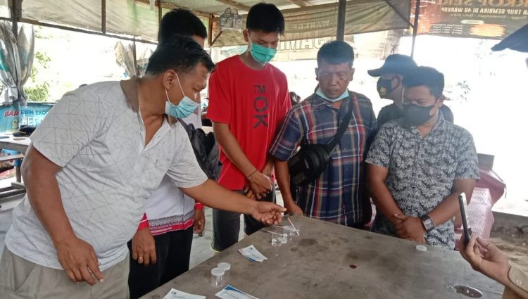 Petugas saat melakukan test urine tiga orang warga yang didapati di lokasi penggerebekan.