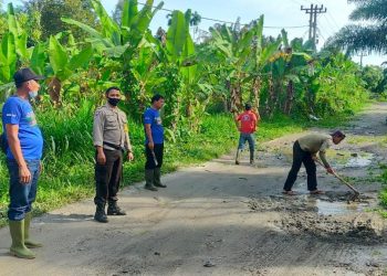 Bripka Nurul Huda bersama dengan Pangulu Nagori Amborokan Panei Raya, J. R. Damanik, serta staf Nagori dan dibantu masyarakat, tampak membersihkan lingkungan, saluran air dan menimbun jalan yang berlobang, di wilayah Dusun 3 Nagori Panei Raya, Kecamatan Raya Kahean.