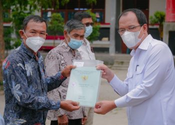 Bupati Humbahas, Dosmar saat menyerahkan sertifikat tanah kepada salah satu perwakilan masyarakat.