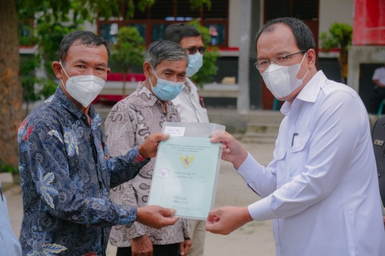 Bupati Humbahas, Dosmar saat menyerahkan sertifikat tanah kepada salah satu perwakilan masyarakat.