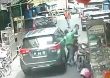 Tangkapan layar pria berseragam ojol mengeroyok pengendara mobil di Medan. [Ist]