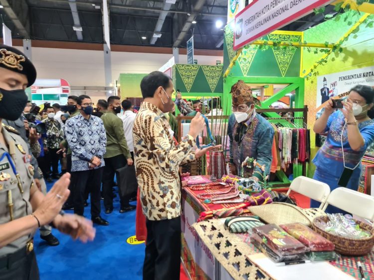 Presiden Jokowi melihat kain ulos yang dipajang di stand Pemko Pematangsiantar dan disaksikan Ketua Dekranasda Kota Pematangsiantar, HK Erizal Ginting, Rabu (23/3/2022).