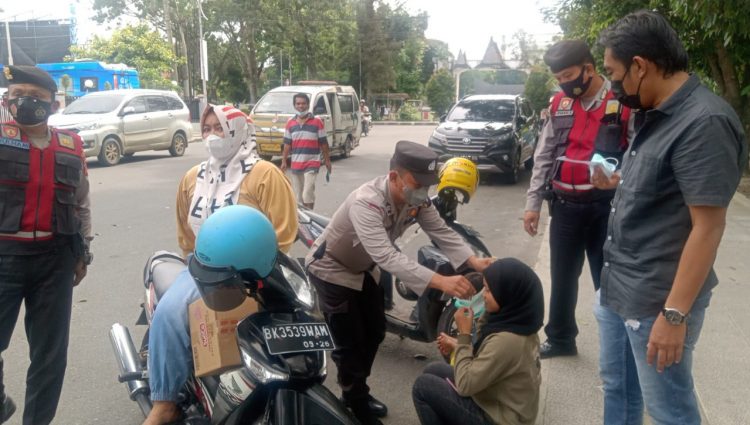 Petugas membagi masker gratis kepada warga.