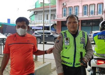 Kanit Reskrim Polsek Delitua Iptu Irwanta Sembiring (Kaos Oranye) saat menggiring Polisi lalulintas gadungan bernama Darwin Antonius Sibarani (37) ke pos lantas Polsek Delitua, Selasa (3/5/2022). Dari tas pelaku ditemukan 15 STNK dan beberapa bukti lainnya. Tribun Medan/ Fredy Santoso