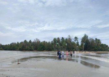Saat pantai dalam keadaan surut dan terbelah, Beberapa pengunjung sedang jalan menuju Pulau Pane. TRIBUN MEDAN/ANISA