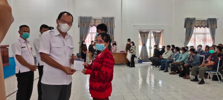 Bupati Humbahas, Dosmar Banjarnahor saat memberikan buku tabungan BSPS kepada salah satu penerima, di Aula Hutamas Komplek Perkantoran Tano Tubu, Kecamatan Dolok Sanggul, Kamis (19/5/2022).